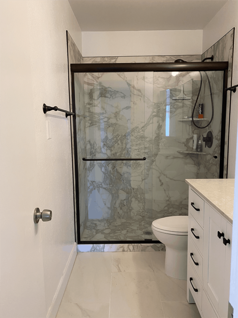 A newly renovated shower stall featuring sleek tiles, a contemporary glass door, and modern fixtures, showcasing a stylish and functional bathroom upgrade.
